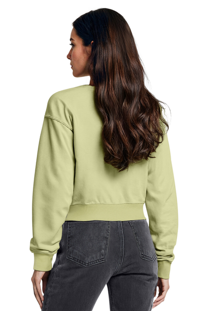 Woman wearing a light green sweatshirt and dark jeans on a white background
