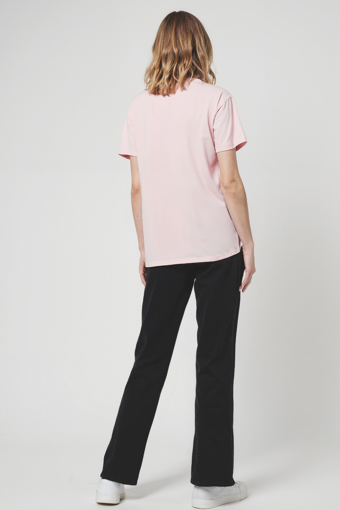 Woman wearing a pink t-shirt and black pants on a white background