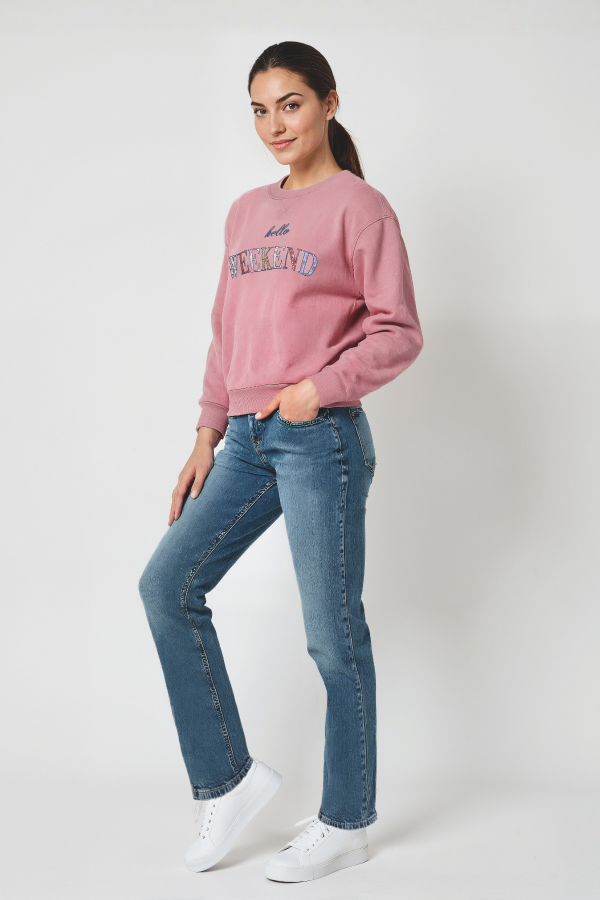Woman wearing a pink sweatshirt and blue jeans on a white background
