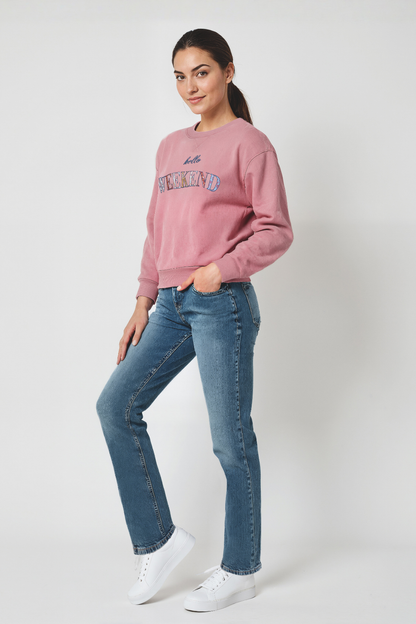 Woman wearing a pink sweatshirt and blue jeans on a white background