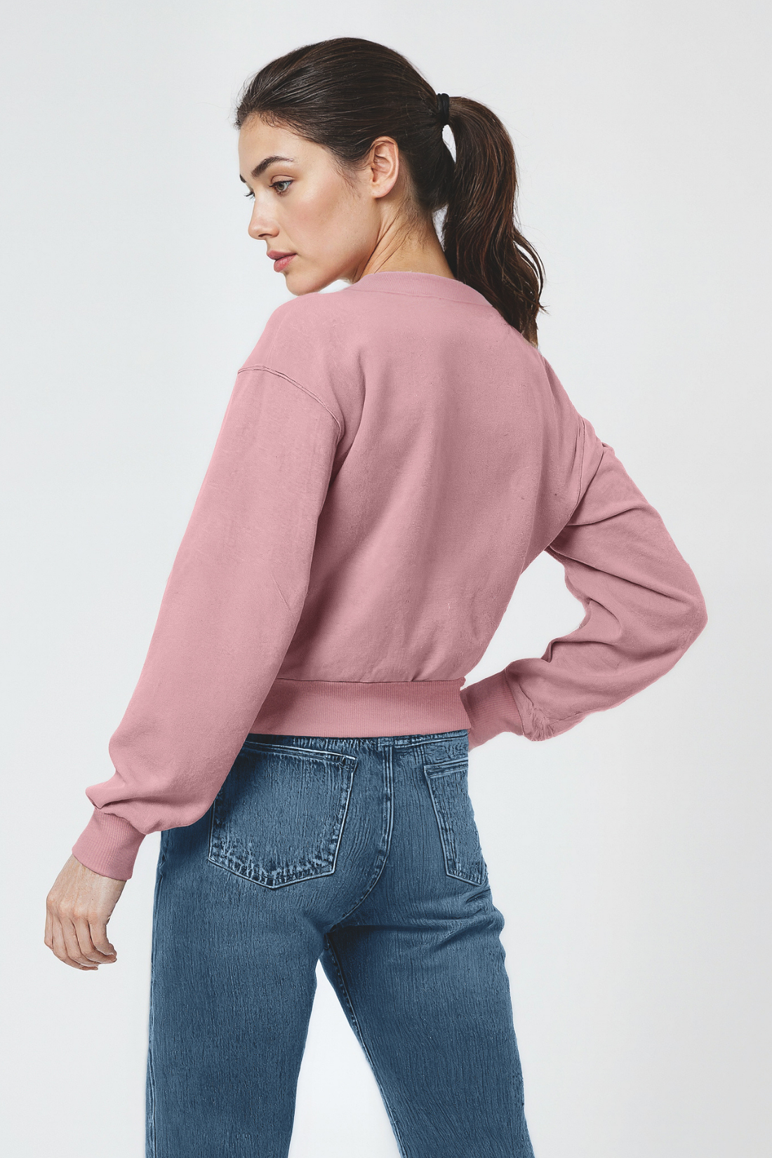 Woman wearing a pink sweatshirt and blue jeans on a white background