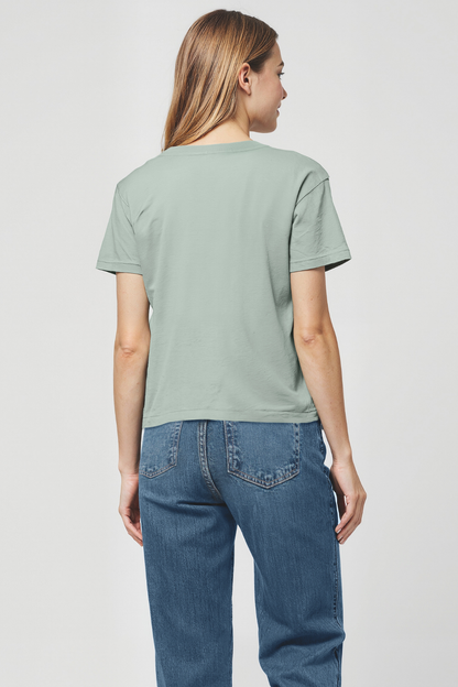 Woman wearing a light green t-shirt and blue jeans on a plain background from the back view
