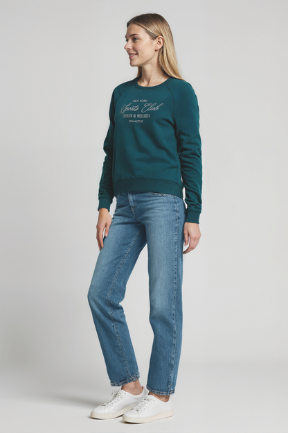 Woman wearing a teal sweatshirt with &quot;New York Sports Club, HEALTH and WELLNESS&