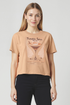 Woman wearing a tan t-shirt with a "Pumpkin Spice Martini" text and pumpkin spice martini graphic on a plain background