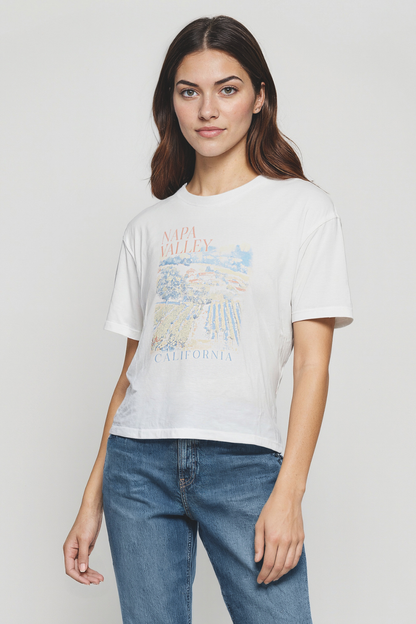 Woman wearing a white t-shirt with a graphic design that reads NAPA VALLEY CALIFORNIA on a plain background