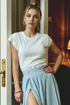 Woman wearing a white t-shirt with a small graphic that has "C&