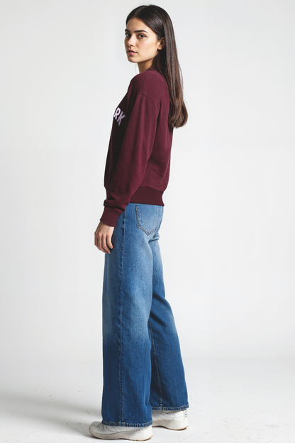 Woman wearing a maroon sweatshirt with &