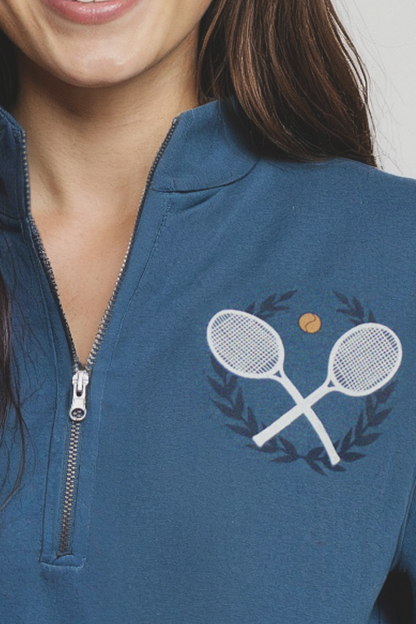 Close up of blue 1/2 zip pullover with tennis racket design on a plain background