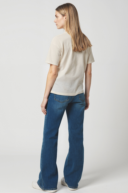 Back of Woman wearing a beige t-shirt and blue jeans on a white background