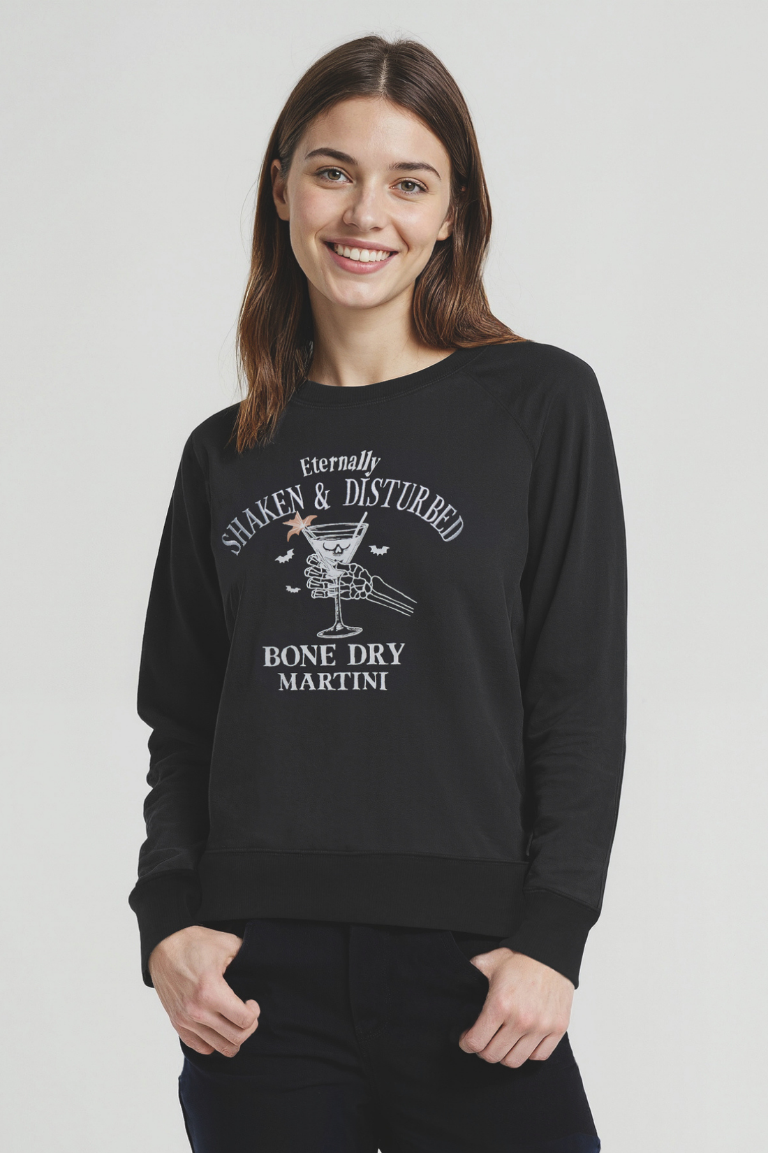 Woman wearing a black sweatshirt with white graphic design of a skeleton holding a martini glass and text &