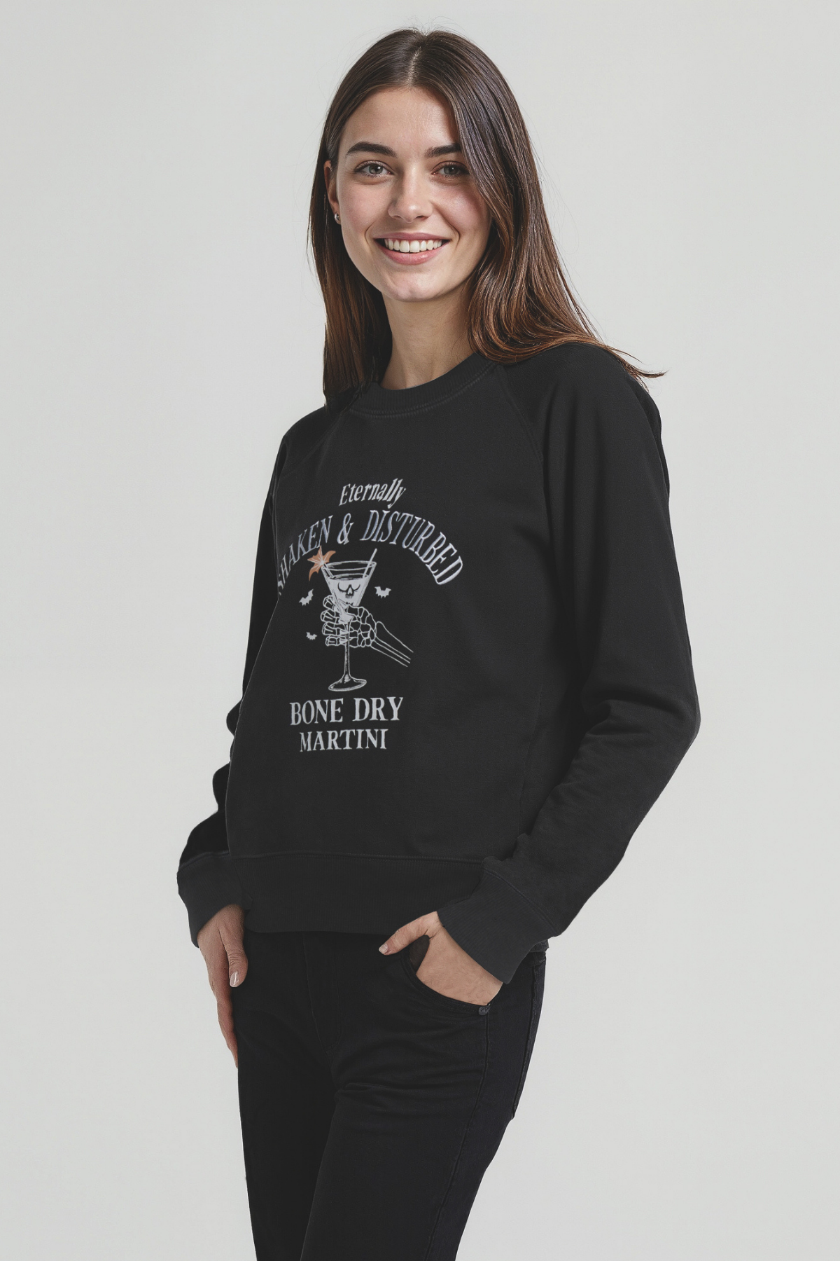 Woman wearing a black sweatshirt with white graphic design of a skeleton holding a martini glass and text &
