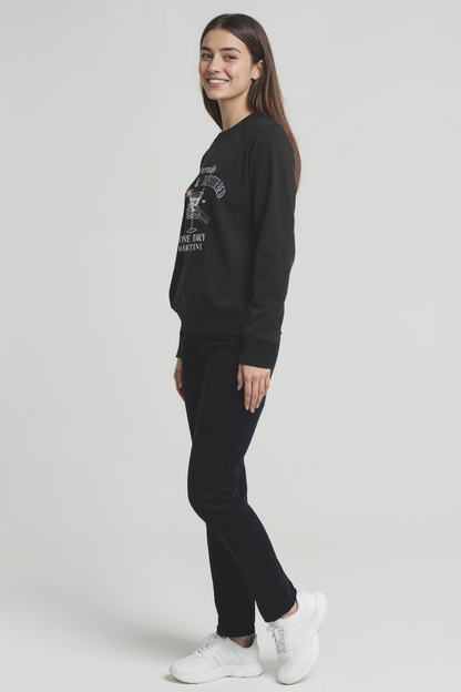 Woman wearing a black sweatshirt and pants with white sneakers on a light gray background