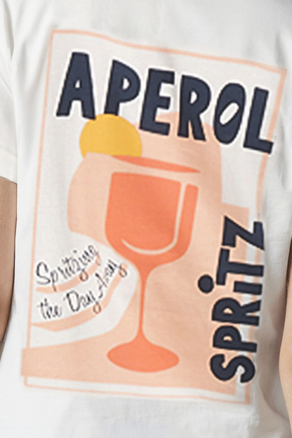 Close up of white T-shirt with &quot;APEROL SPRITZ, Spritzing the Day Away&quot; text and cocktail glass graphic design on a white background