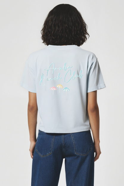Woman wearing a light blue t-shirt with colorful text and graphics on the back, standing against a plain background.
