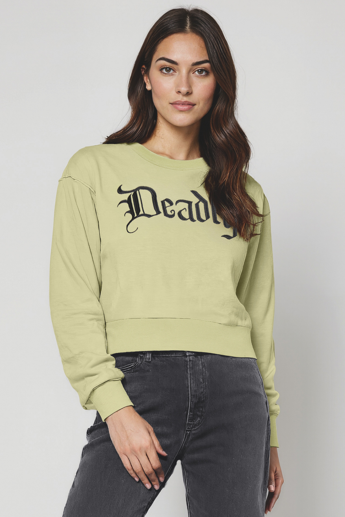 Woman wearing a light green sweatshirt with &