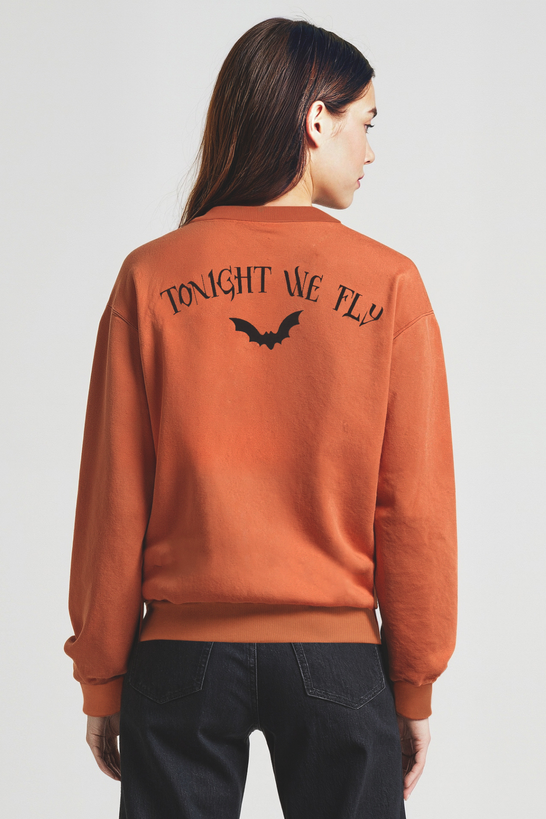 Woman wearing a rust-colored sweatshirt with &