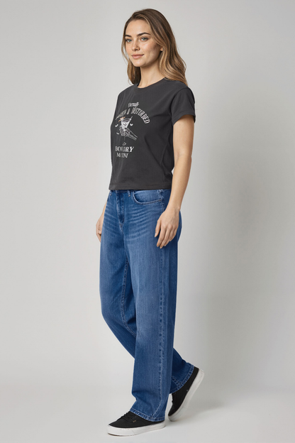 Woman wearing a black t-shirt and blue jeans on a gray background