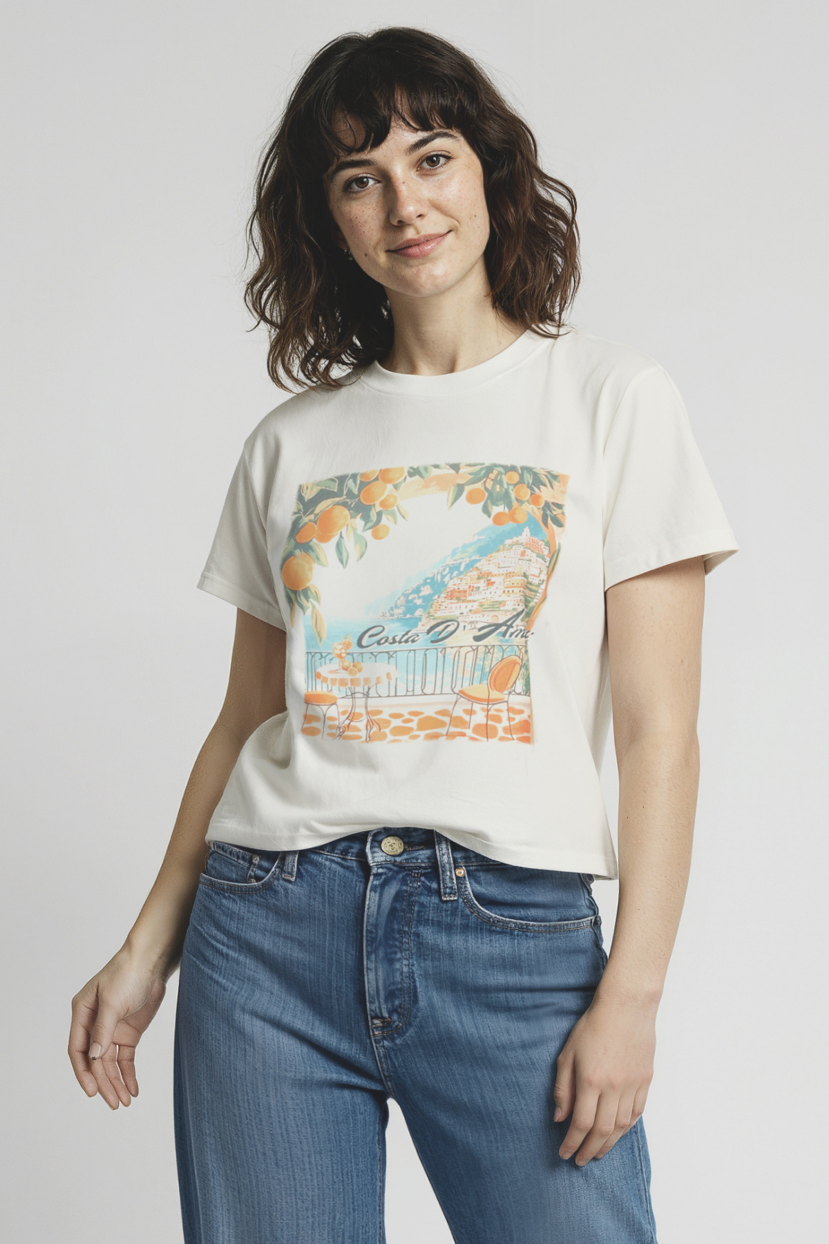Woman wearing a  with a colorful graphic of a coastal scene and &