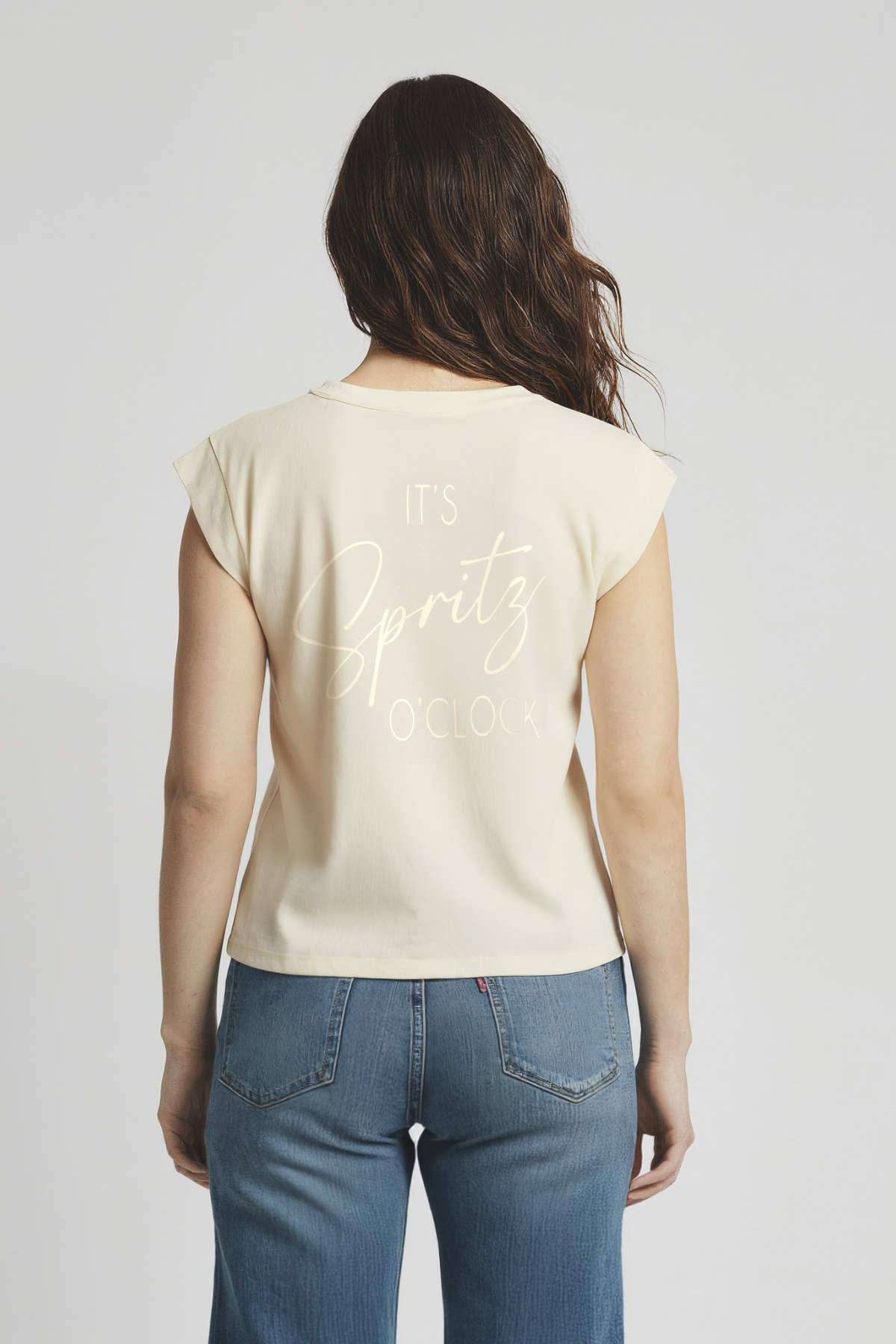 Back of woman wearing a beige sleeveless top with &