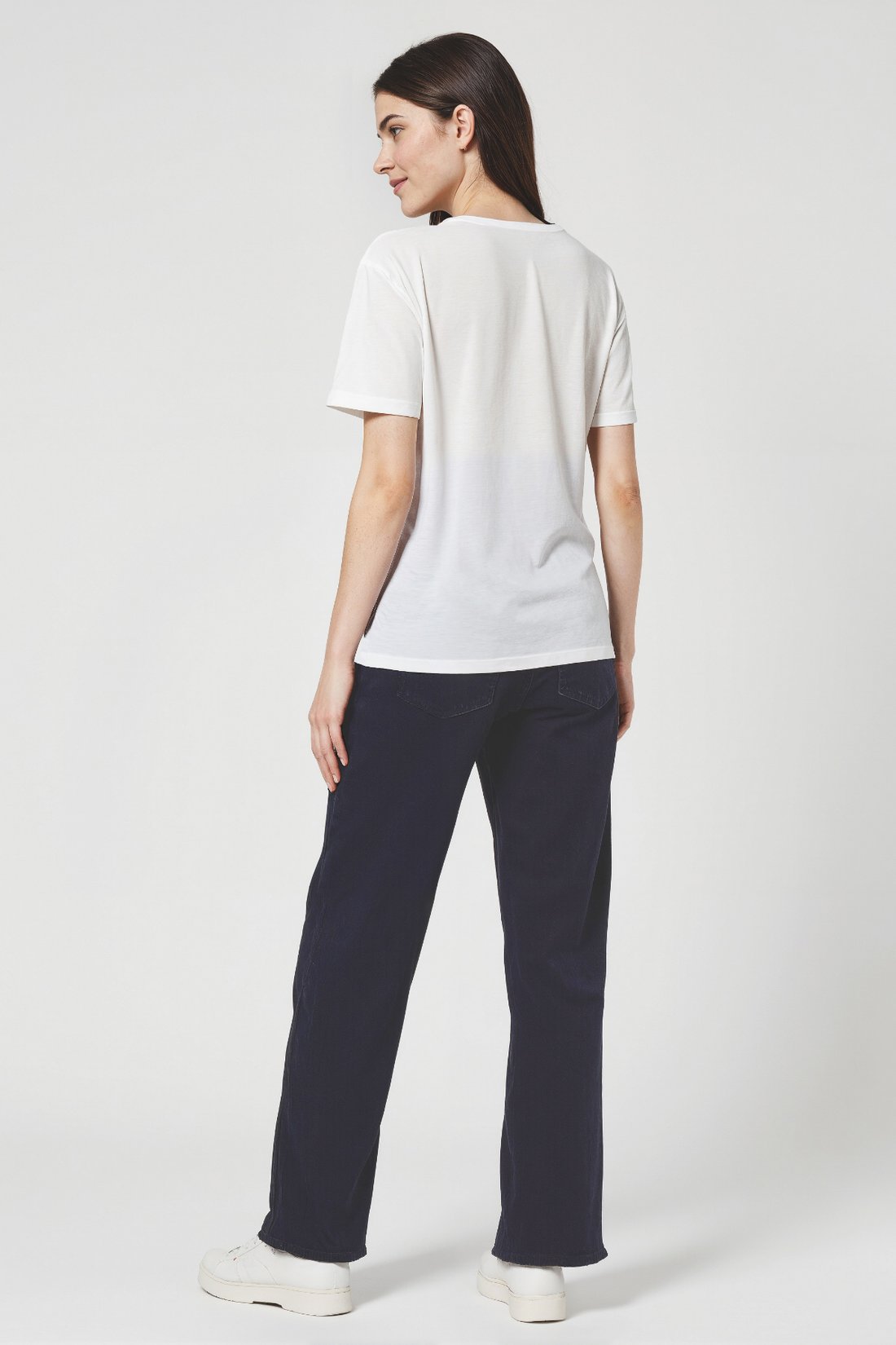 Woman wearing a white t-shirt and navy pants on a white background
