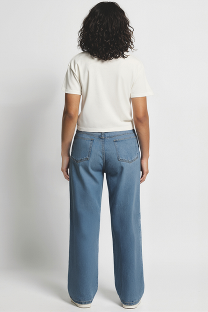 Back of woman wearing a white t-shirt and blue jeans on a plain background
