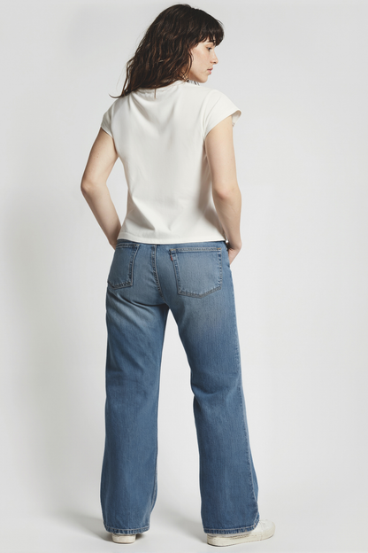 Back of woman wearing a white t-shirt and blue jeans on a white background
