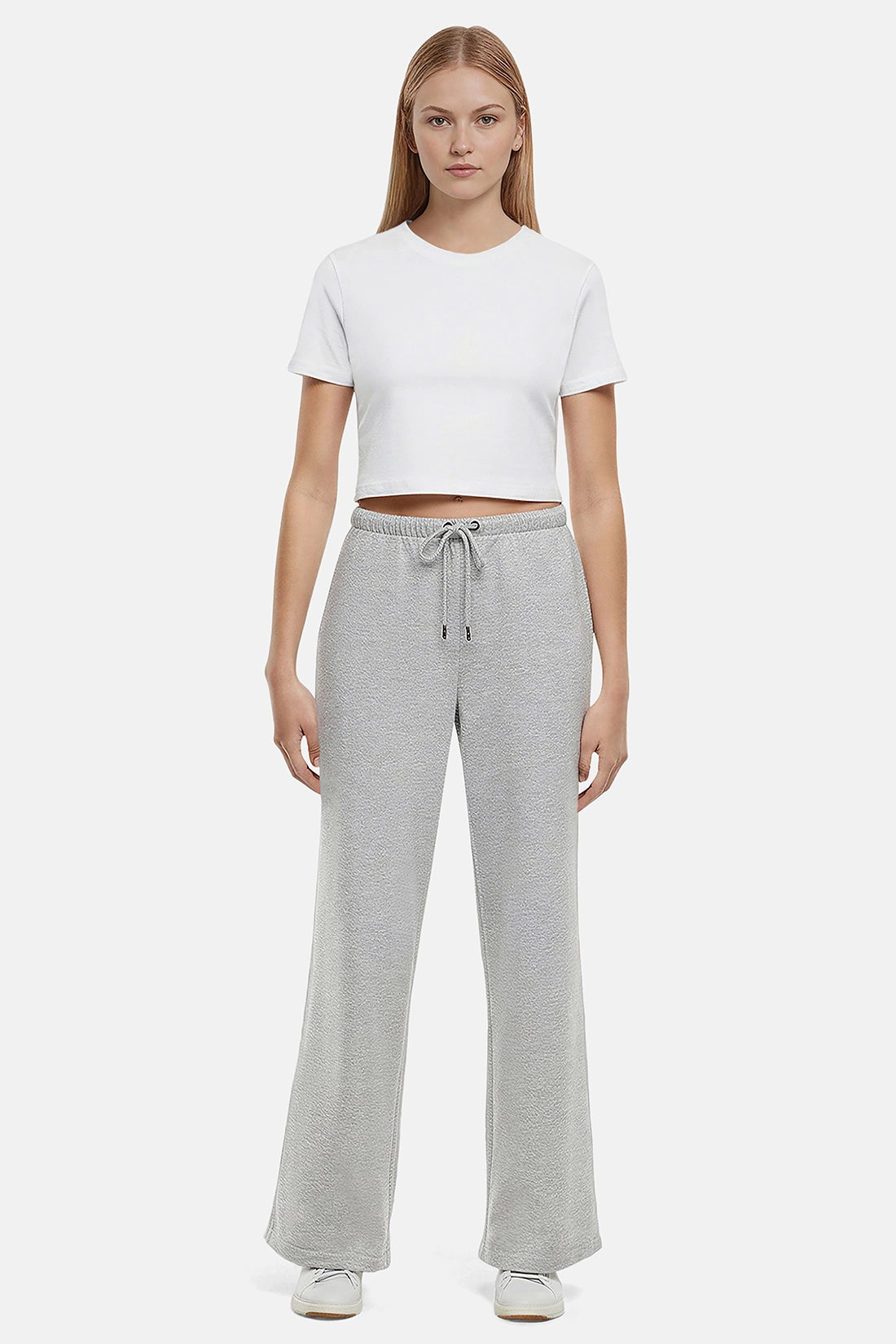 Woman wearing a white cropped t-shirt and heather grey wide-leg drawstring sweatpants on a white background