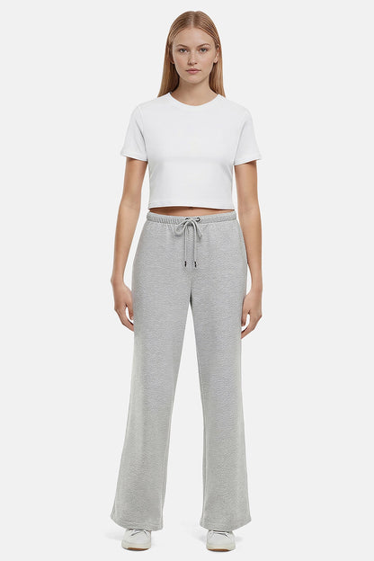 Woman wearing a white cropped t-shirt and heather grey wide-leg drawstring sweatpants on a white background