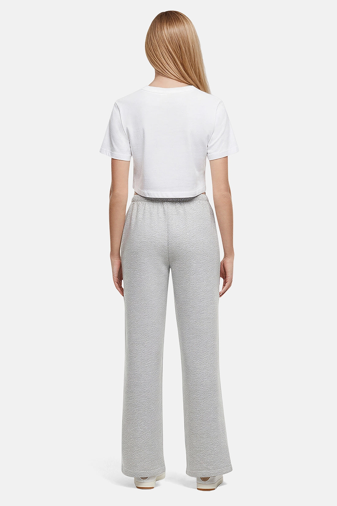 Back of woman wearing a white cropped t-shirt and heather grey wide-leg drawstring sweatpants on a white background
