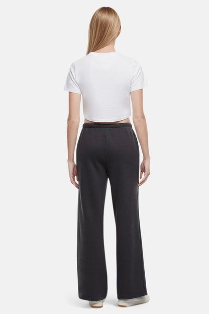 Back of woman wearing a white cropped t-shirt and heather black wide-leg drawstring sweatpants on a white background