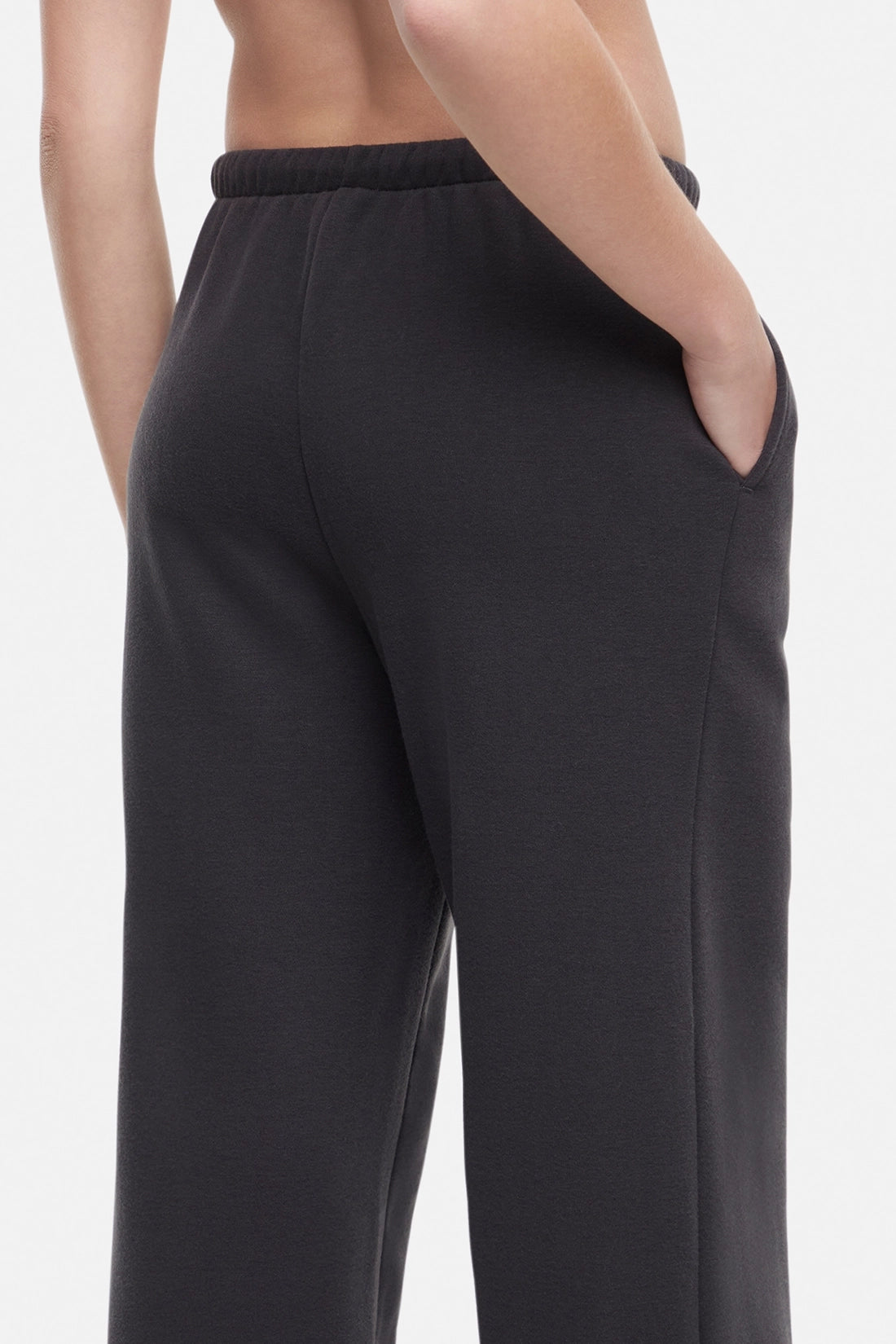 Back close up of woman wearing a white cropped t-shirt and heather black wide-leg drawstring sweatpants on a white background