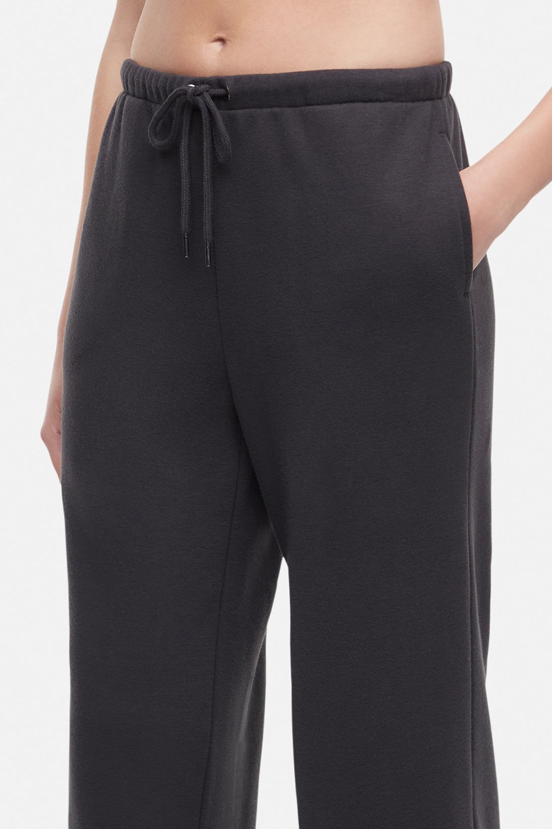 Front close up of woman wearing a white cropped t-shirt and heather black wide-leg drawstring sweatpants on a white background