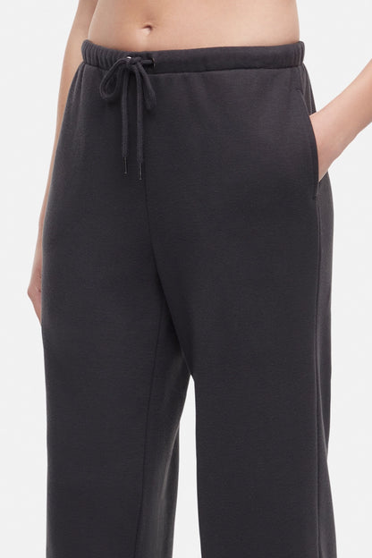 Front close up of woman wearing a white cropped t-shirt and heather black wide-leg drawstring sweatpants on a white background