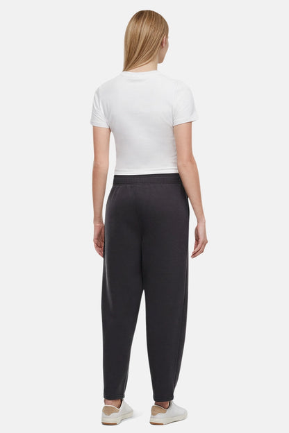 Back of woman wearing a white t-shirt and black tapered leg pants on a white background