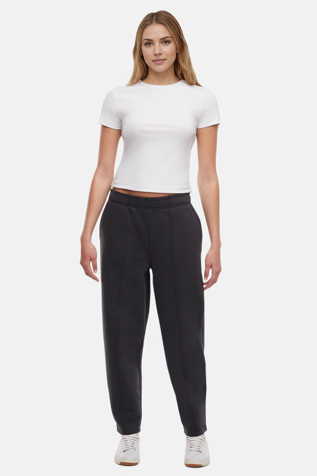 Woman wearing a white t-shirt and black tapered leg pants on a white background