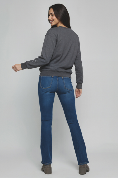 Woman wearing a gray sweater and blue jeans on a plain background