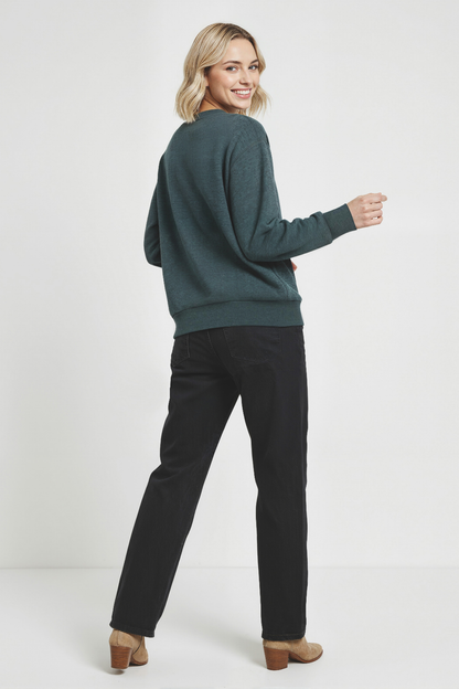 Back of woman wearing a green sweatshirt and black pants on a white background