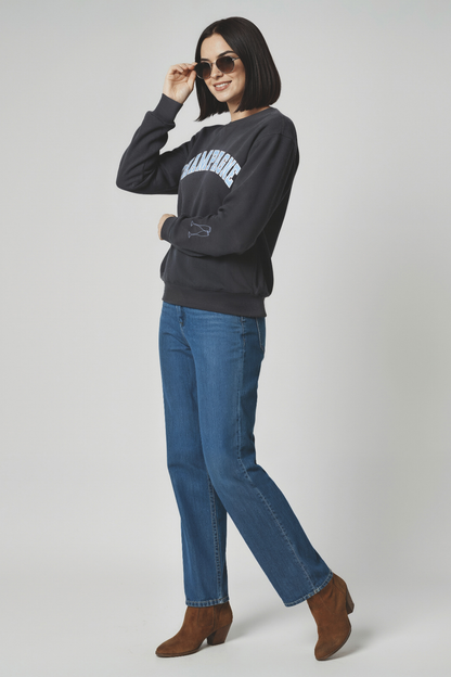 Woman wearing a dark gray sweatshirt with Champagne text, blue jeans, and brown boots on a white background