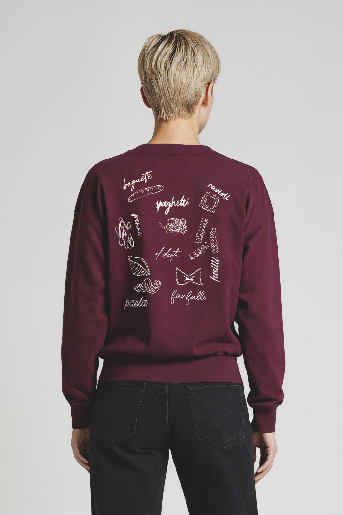 Back of woman wearing a maroon sweatshirt with Italian word designs on the back against a plain background