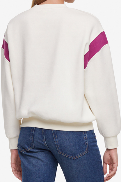 Back of woman wearing a white sweater with purple accents and blue jeans on a white background