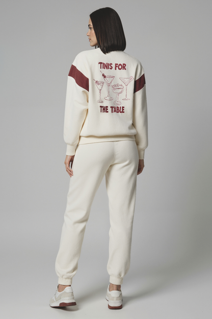 Woman wearing a cream sweatshirt with red 4 cocktails graphic and text &