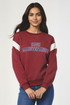 Woman wearing a maroon sweatshirt with &