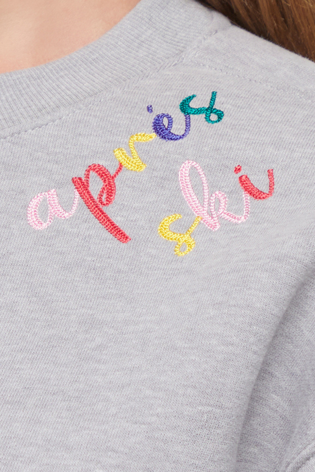 Close up of gray sweater with colorful embroidered &