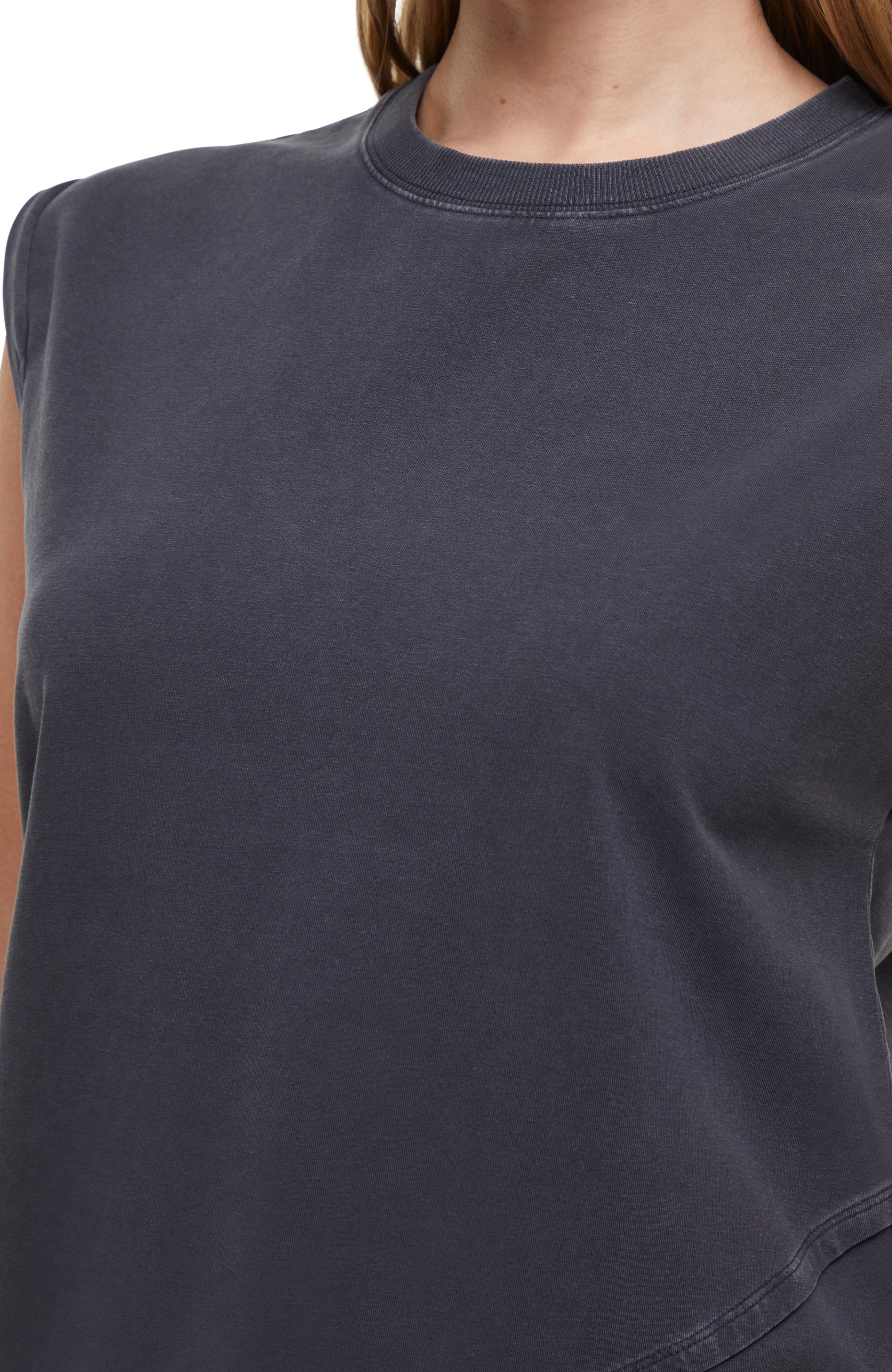 Close up front view of woman wearing a dark gray sleeveless asymmetrical top and pants on a white background. 