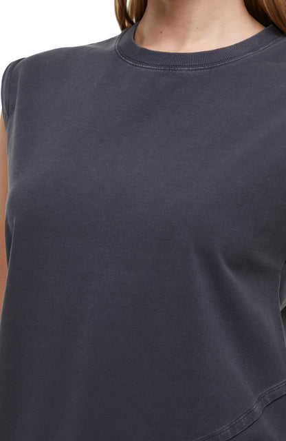 Close up front view of woman wearing a dark gray sleeveless asymmetrical top and pants on a white background. 