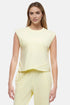 Front view of woman wearing a light-yellow sleeveless asymmetrical top and pants on a white background. 