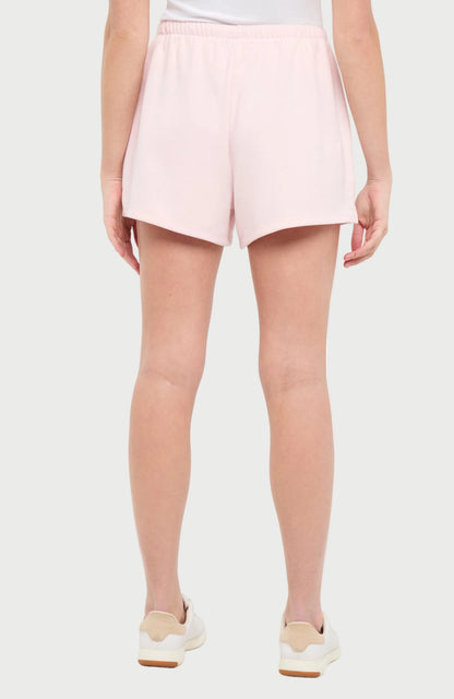 Back view of woman wearing light pink shorts on a white background. 