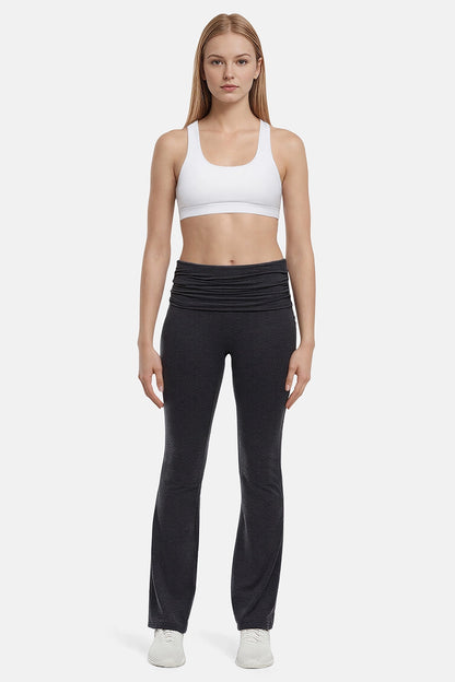 Woman wearing a white sports bra and black yoga pants on a white background