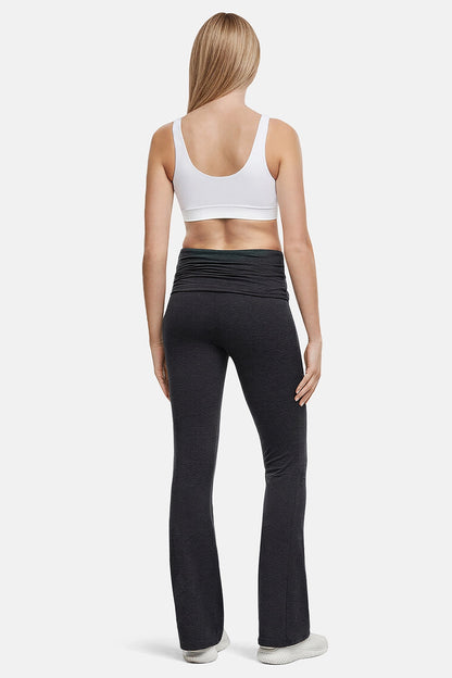 Back of woman wearing a white sports bra and black yoga pants on a white background