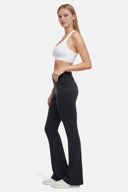 Side view of woman wearing a white sports bra and black high-waisted yoga pants on a white background
